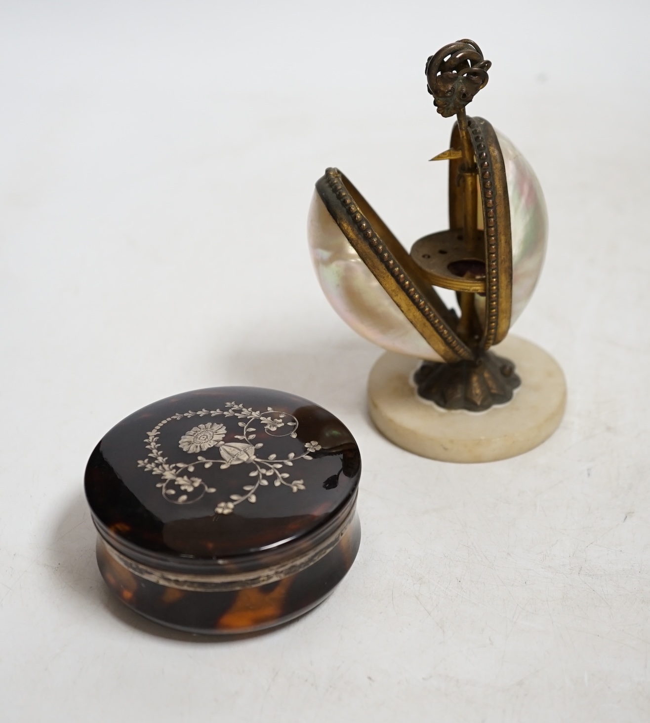A Victorian tortoiseshell and silver piqué inlaid circular lidded snuff box and a Palais Royale mother-of-pearl and ormolu needlework case, largest 13cm high. Condition - fair, case does not snap shut